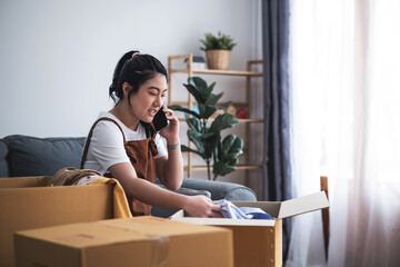 New house, asian woman put the stuff in the box while feeling proud and excited about buying a house with a mortgage loan. Young asian woman first time buyers unpacking in dream home or apartment