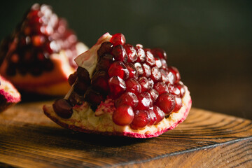 Appetizing piece of sweet pomegranate macro on cutting board on dark background