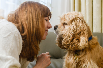 Close-up of the face of the girl and the muzzle of the spaniel in front of each other.