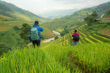 Fototapeta na wymiar Tourists are standing on the viewpoint and take picture of rice terraces scenery at Mu Cang Chai in the north of Vietnam.