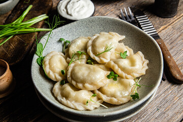 Vareniki with feta and herbs in a plate on a wooden table