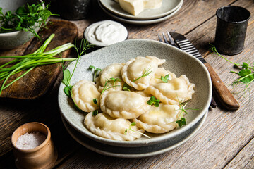 Vareniki with feta and herbs in a plate on a wooden table