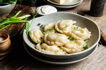 Vareniki with feta and herbs in a plate on a wooden table