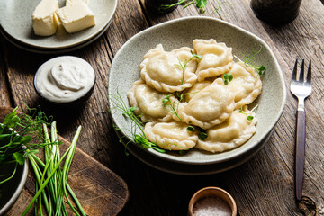 Vareniki with feta and herbs in a plate on a wooden table