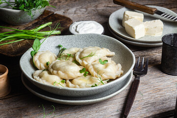 Vareniki with feta and herbs in a plate on a wooden table