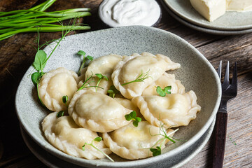 Vareniki with feta and herbs in a plate on a wooden table