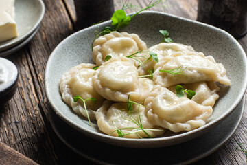 Vareniki with feta and herbs in a plate on a wooden table