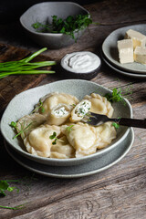 Vareniki with feta and herbs in a plate on a wooden table