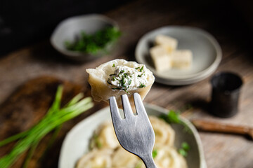 Vareniki with feta and herbs in a plate on a wooden table