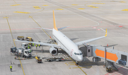 Airplane at airport being loaded, serviced and refueled 