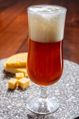 Glass of Belgian light blond beer made in abbey and tasty belgian cheese