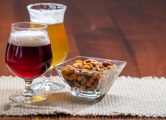 Glasses of Belgian yellow blond and dark brown beer made in abbey served in bar with party nuts