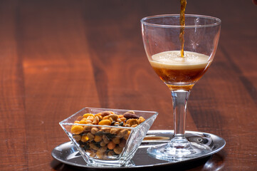 Glass of Belgian abbey brown beer with snack nuts in bar