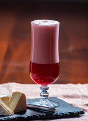 Glass of Belgian fruity red sour cherry kriek beer and soft belgian cheese, pairing of cheese and beer in Belgium