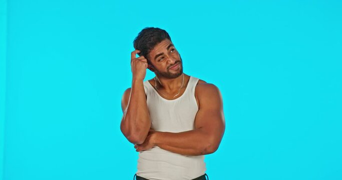 Thinking, confused and shrug with a man on a blue background in studio to make a decision. Idea, doubt and problem solving with a handsome young male scratching his head, clueless about a though