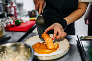 Chef cooking Roasted salmon steak with pumpkin cream on restaurant kitchen