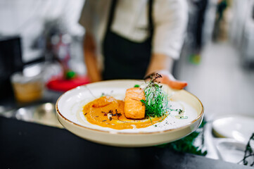 Chef cooking Roasted salmon steak with pumpkin cream on restaurant kitchen