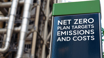 Net zero  plan targets emissions and costs on a sign in front of an Industrial building	