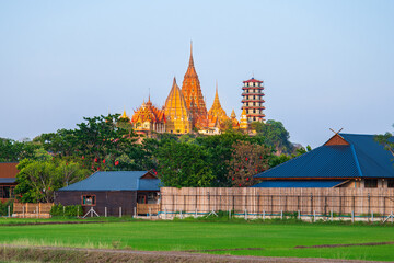 Naklejka premium Wat Tham Seua temple with green rice filed in the sunset time at Kanchanaburi Thailand