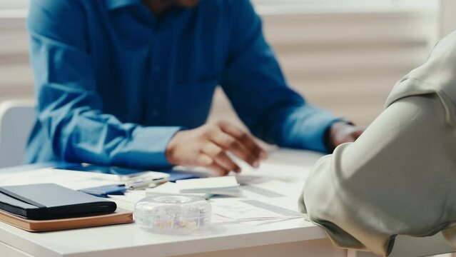 African American male interviewer talking with job candidate, gesturing hands