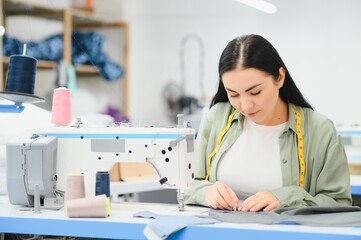 Young woman working as seamstress in clothing factory.