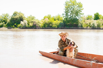 Caring male angler petting cute setter pet, while boat trip on calm lake. Front view of man, owner...