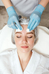 Beautician cleanse and moisturize the face of young female