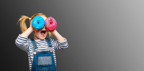 Happy cute girl is having fun played with donuts on black background wall.