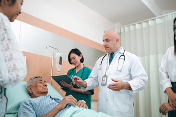 professional doctor standing by explain the treatment information via male elderly patient lying in...