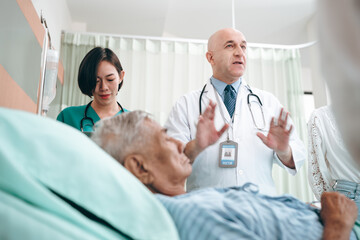 Obraz premium professional doctor standing by explain the treatment information via male elderly patient lying in bed in private hospital sickroom. The treatment program is suitable for people to socialize elderly
