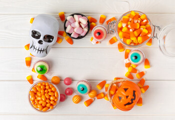 Fototapeta premium Halloween candy corn,jelly eye, pumpkin candy, sugar skull in different bowls on white background.Classic candy sweets for Halloween with.Halloween holiday concept with candy corn and jack o lantern.