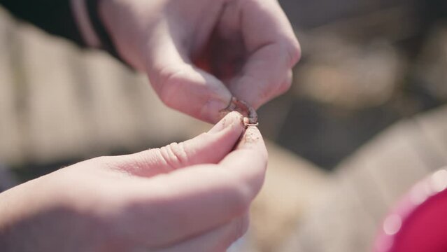 a man puts a worm on a hook close-up