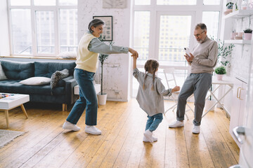 Positive family dancing in living room at home