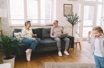 Obraz premium Happy aged couple spending time with granddaughter