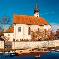 Church on a sunny summer day with reflections on a car roof at Ettling, Isar, Bavaria, Germany