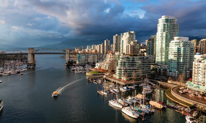 Fototapeta premium Aerial View of Granville Island in False Creek with modern city skyline and mountains in background. Downtown Vancouver, British Columbia, Canada. Sunset Sky