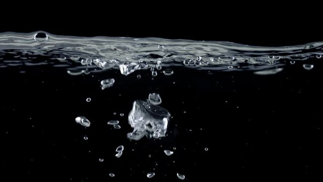 Surface of water on black background, air bubbles rise up. Slow motion shot of boiling water