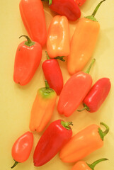 red, orange and yellow peppers in a yellow background 