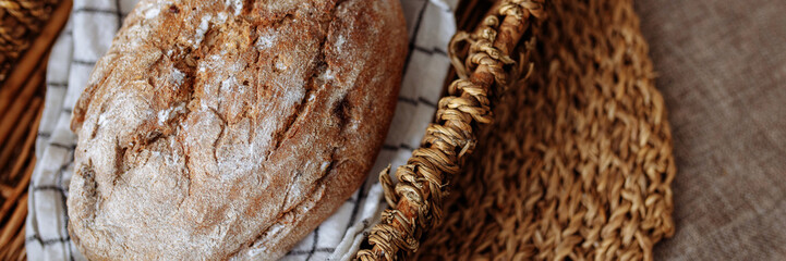 Bread background. Homemade bread with seeds and bran. Healthy bread in a wicker basket on the kitchen table. Cereal products of hand baking. Banner for website header design with copy space.