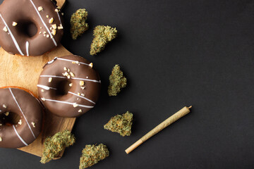 Chocolate-coated donuts with hazelnut topping lie on a wooden board among dry buds of medical...