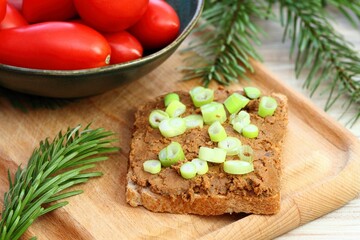 Pate spread from deer meat on whole grain bread  and green onion on top. Sandwich with meat pate on cutting board, fresh tomatoes. Decorated with spruce branches.