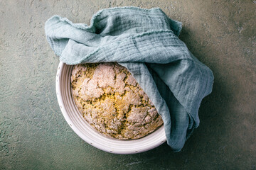 Homemade spelt bread with herbs and wild garlic, process of raising dough in a special basket