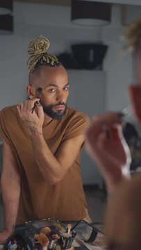 Black brazilian gay applaying make up eyeshadow looking mirror view from behind. Non binary guy. LGBT People lifestyle fashion lgbtq concept Vertical video