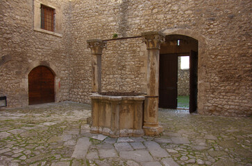 Obraz premium Piccolomini Castle of Capestrano (AQ - 15th-century marble well, flanked by columns with foliate capitals.