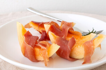 Fototapeta na wymiar plate with appetizer with melon and jamon on the table
