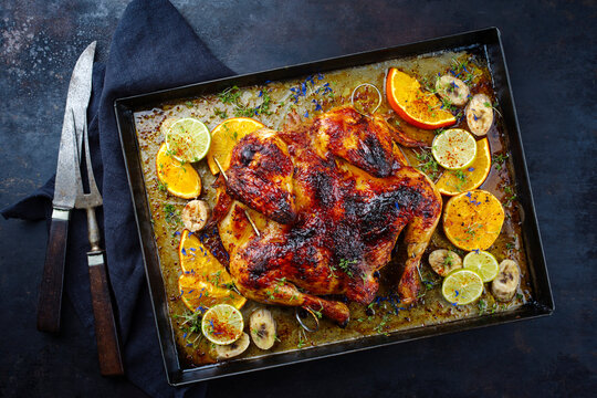 Traditional barbecue spatchcocked chicken al mattone chili with orange, lime and banana slices served as top view on an old rustic metal tray