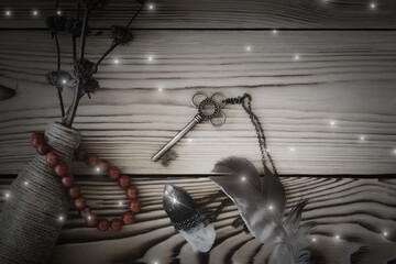 Fototapeta na wymiar Magic tools on wooden background, a key, black quartz, bottle, feather and jasper bracelet.