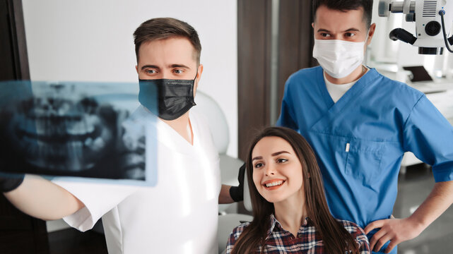 Dentist and his assistant explain details of the x ray image to the patient
