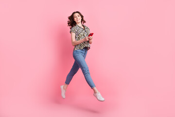 Full body portrait of excited crazy lady use smart phone jumping empty space isolated on pink color background