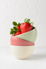 Juicy strawberry in colorful cups on a white background is the concept for any kind of diet and healthy eating. Closeup, copy space for text